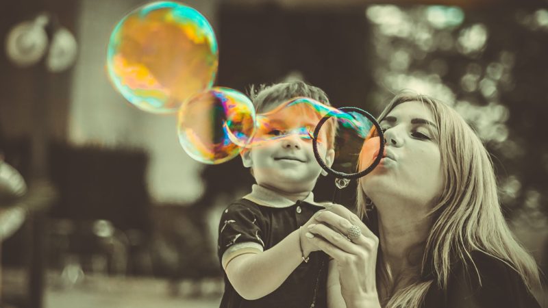 A mother and young son blowing bubbles together