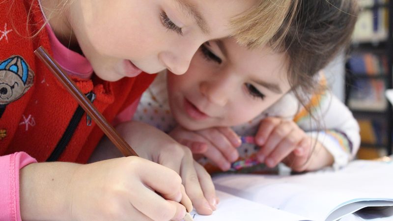 Two children drawing together at a table