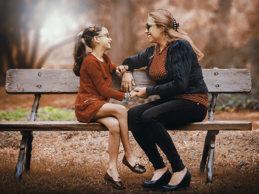 A mother and daughter talking together on a park bench