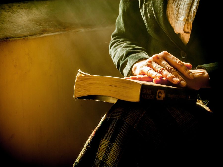 Hands resting on open scriptures in warm light